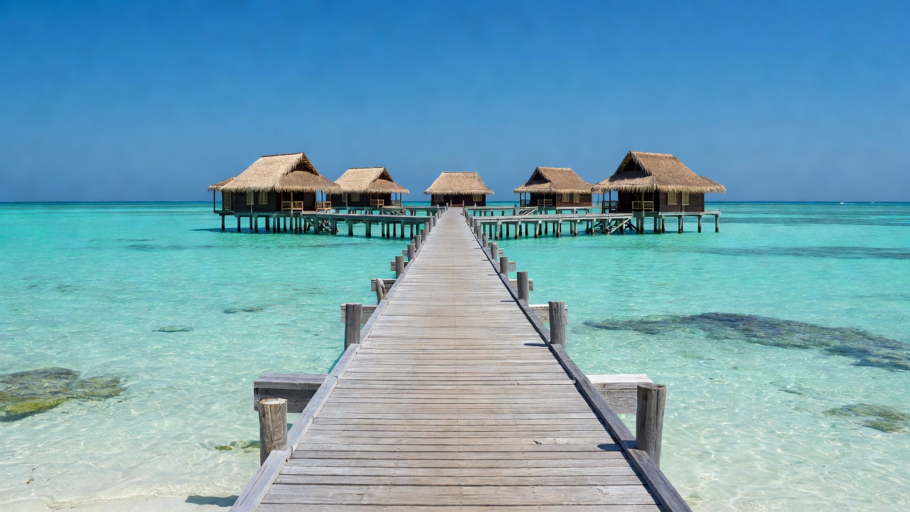 Wooden jetty stretching over a turquoise lagoon toward island villas